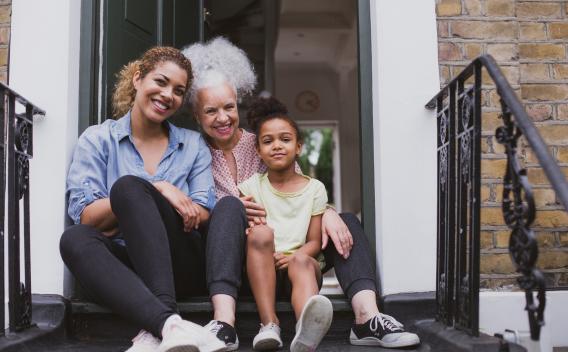 A family of three sits on their front steps. 