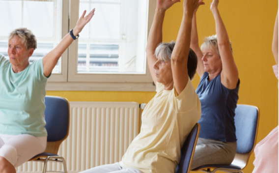 Older adults performing chair yoga in an indoor studio