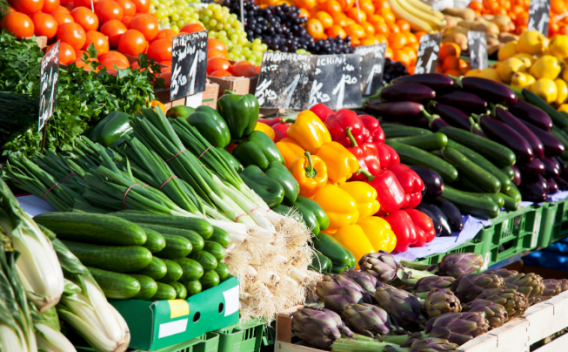 Fresh fruits and vegetables displayed on a farmers' market stand. 